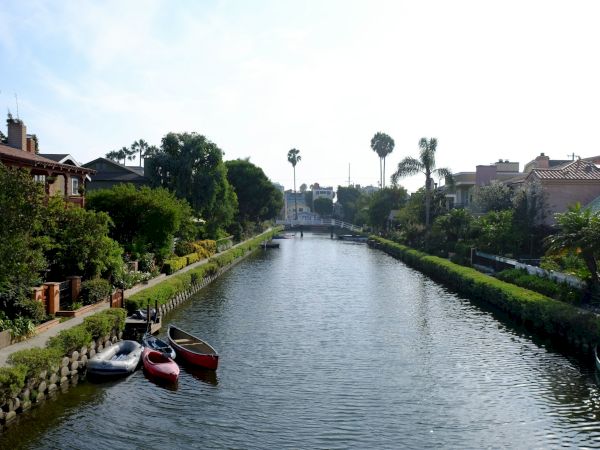 The image shows a peaceful canal lined with trees, houses, and small boats, creating a serene and picturesque setting.